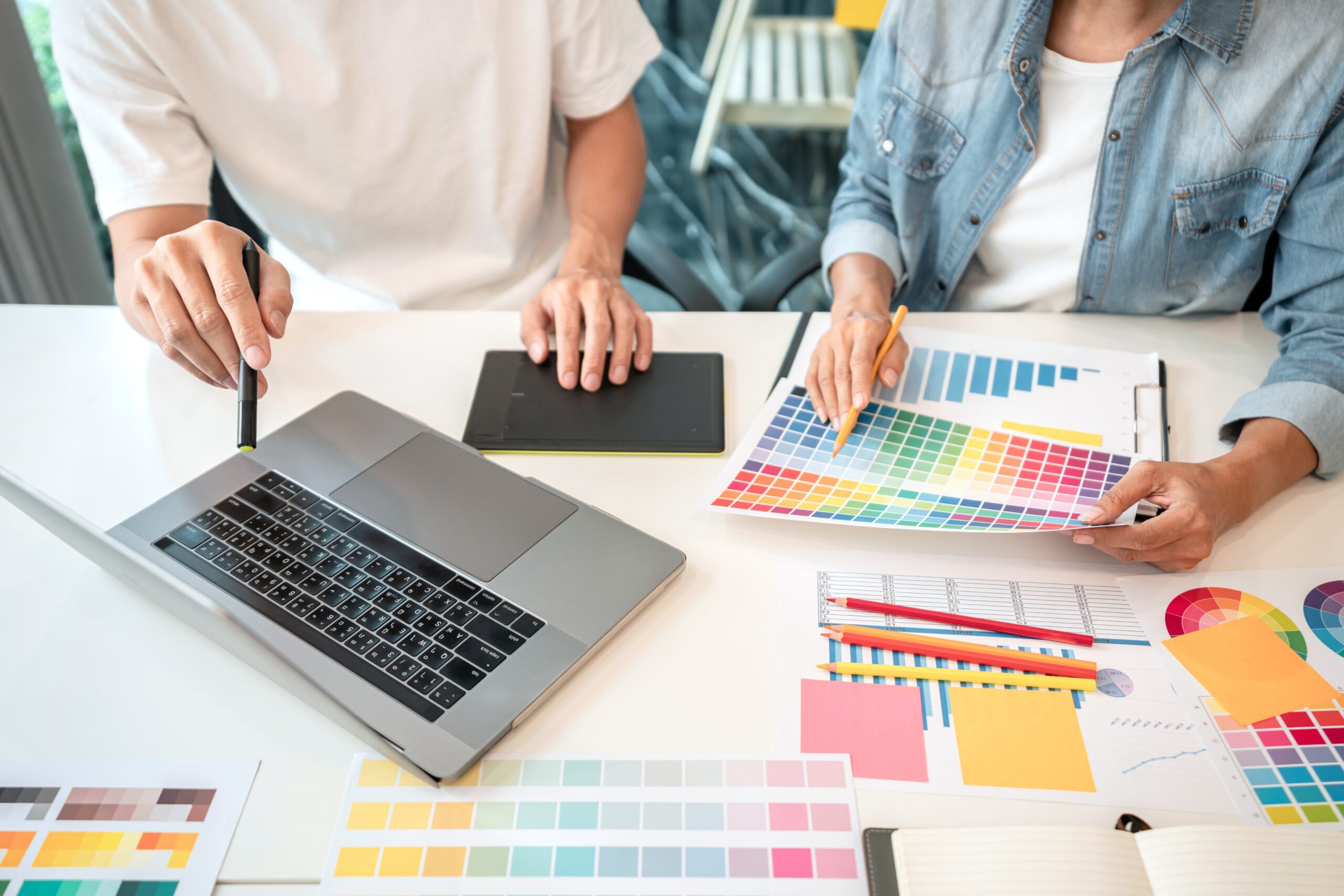 Team of creative graphic designer working on color swatch samples chart for selection coloring in inspiration to create new collection at workplace.